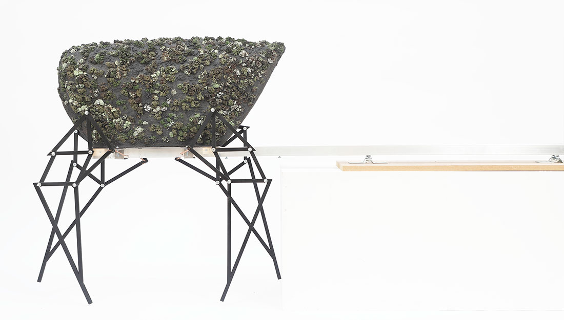 An table-like structure holds a surface covered in ceramic 'moss'.