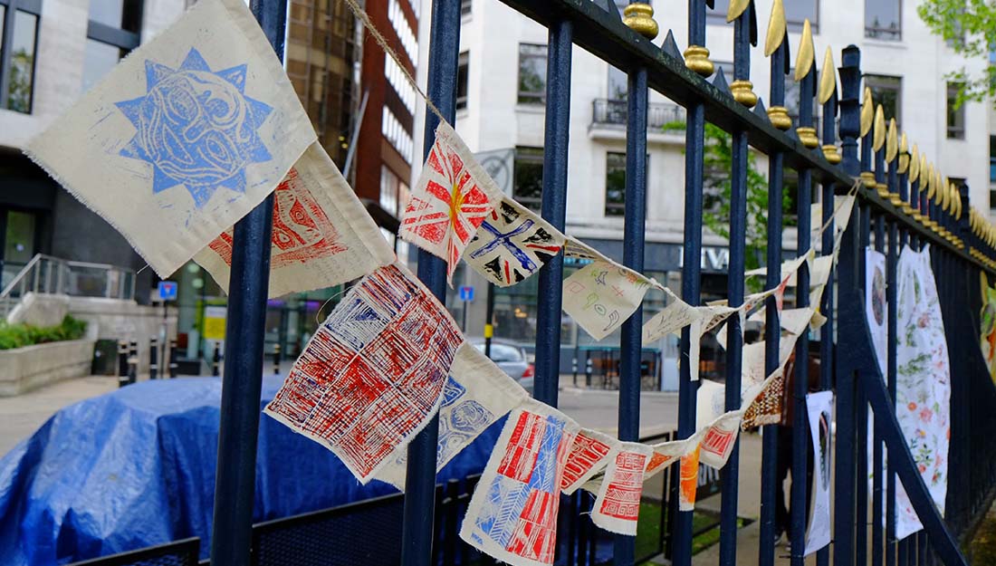 a selection of hand printed fabric flags are hung on string on a dark blue railing