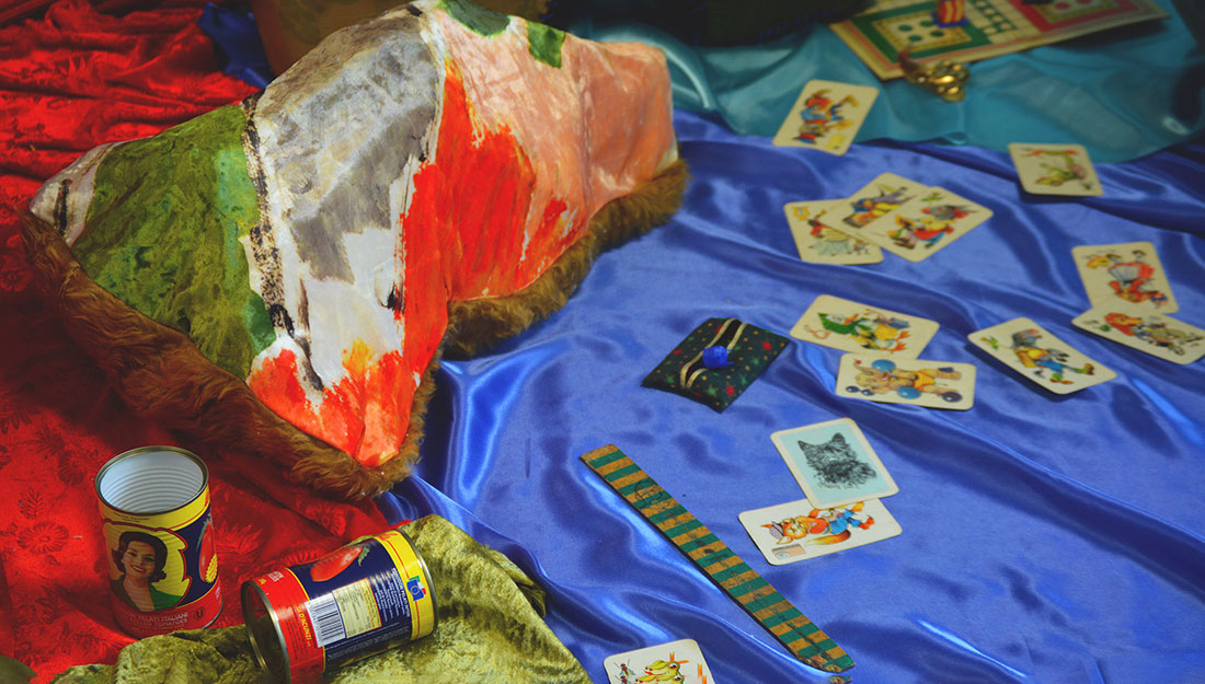 A colourful scene of draped textiles, tarot cards and bright tin cans.