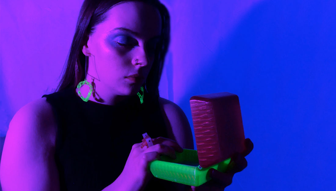 A woman looks at a box, it is glowing in the ultra violet light.