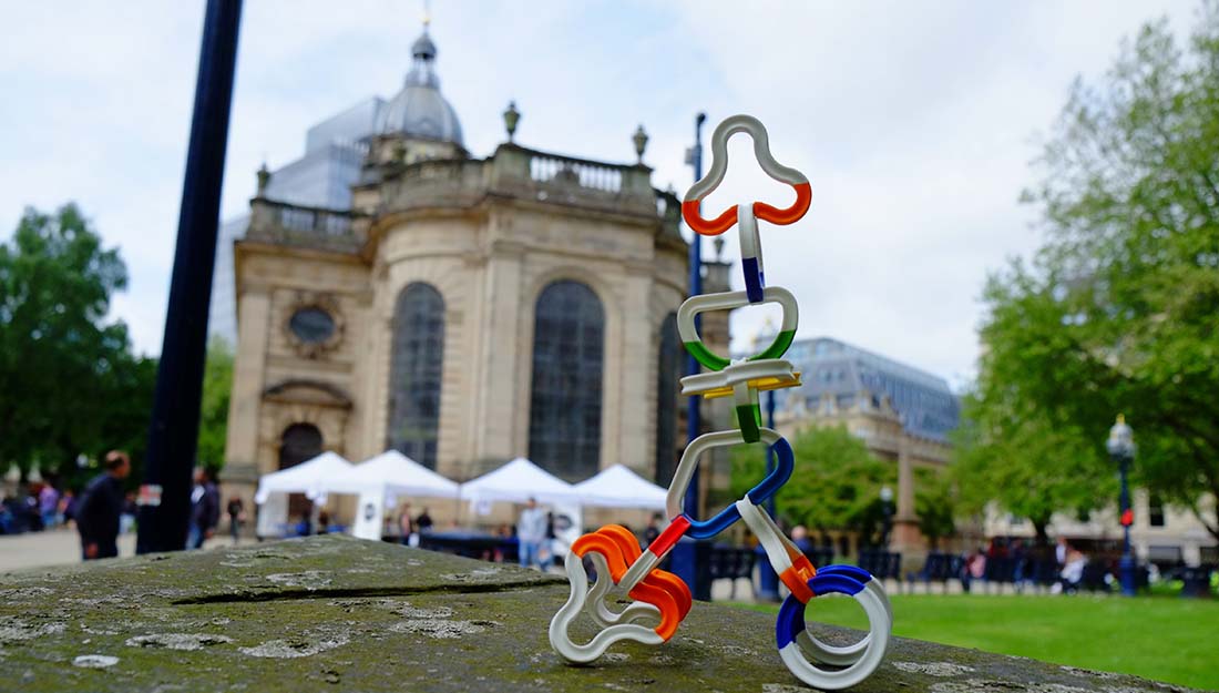 a structure created from linkable plastic forms in the foreground. A cathedral and park visible in the background.
