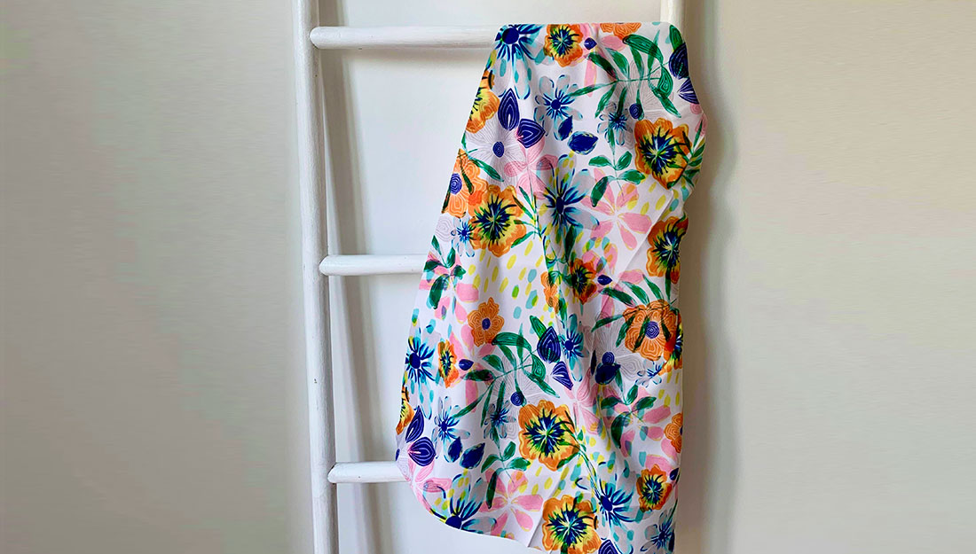 A flowery fabric hangs on a white ladder.