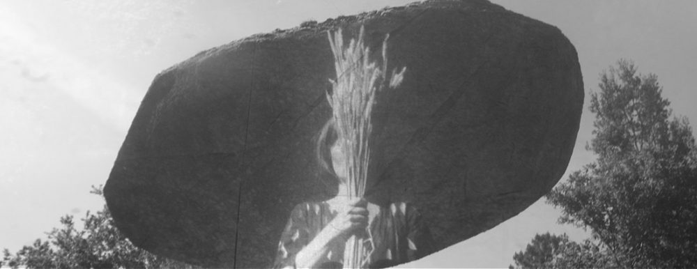 Layered black and white images with a ghostly feel. The main background images is a large balanced stone, in front a woman hold a bunch of wheat in front of her face.