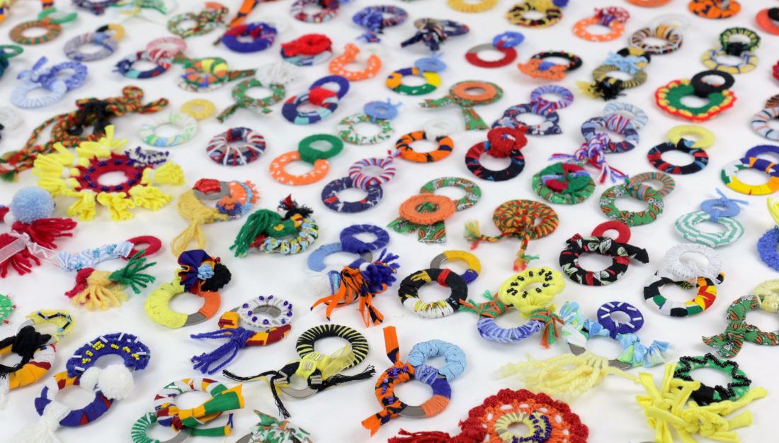 a large selection of handmade textile objects made up of two rings wrapped in a variety of colourful yarns.
