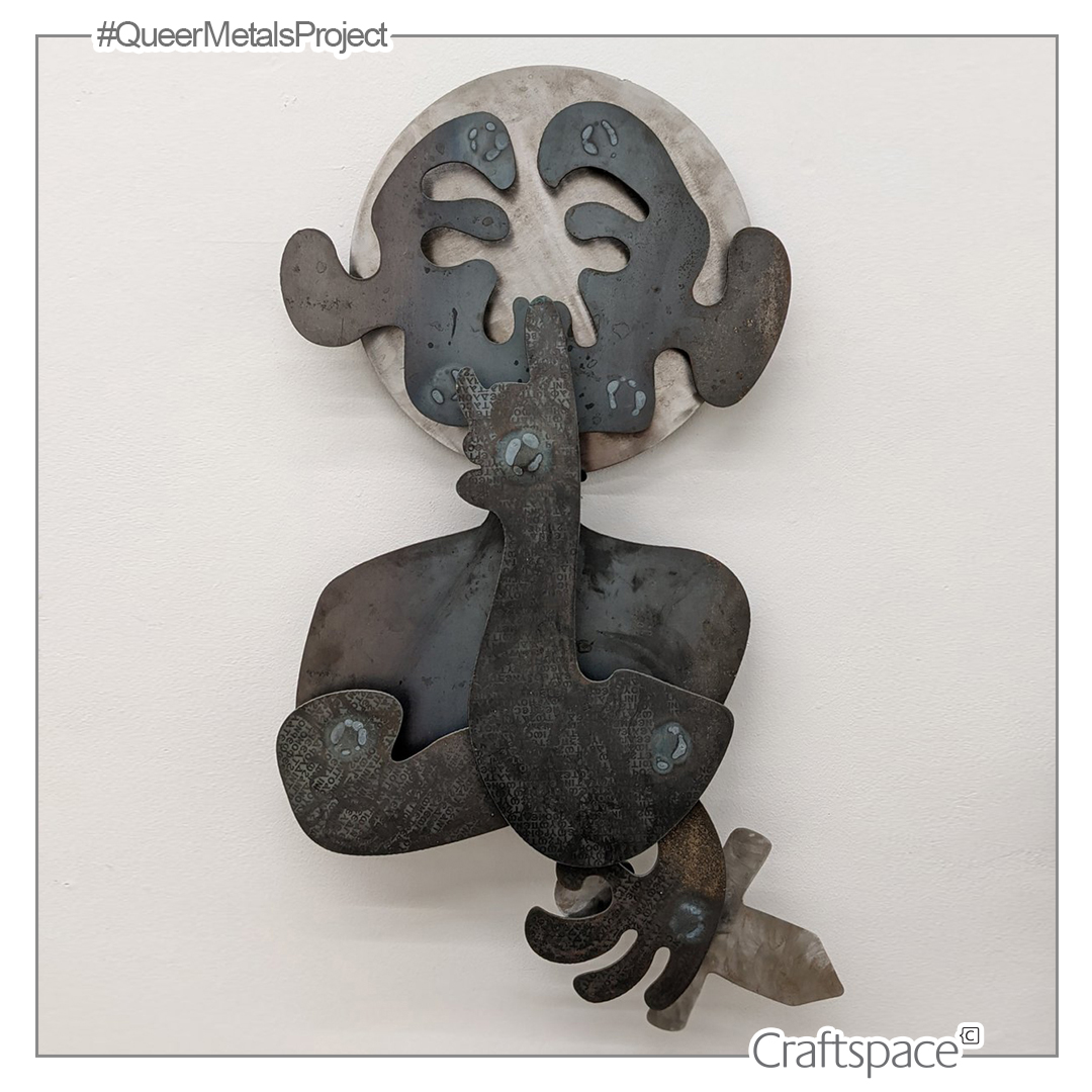 a figure made from layered metal cutouts holds a small sword in one hand while their chin rests on the other