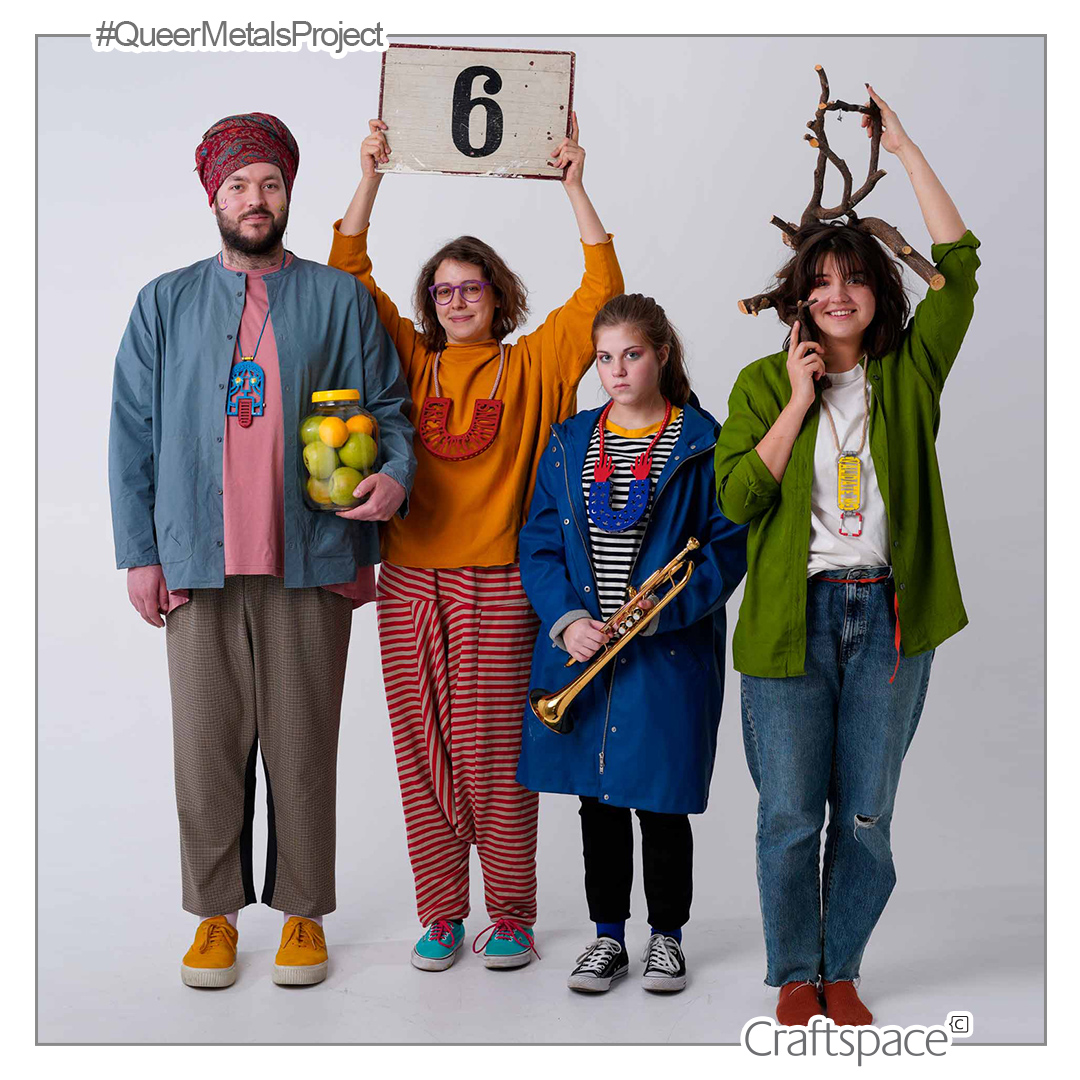 four people stand together, one person holds a sign with the number 6 and another holds antlers on her head.