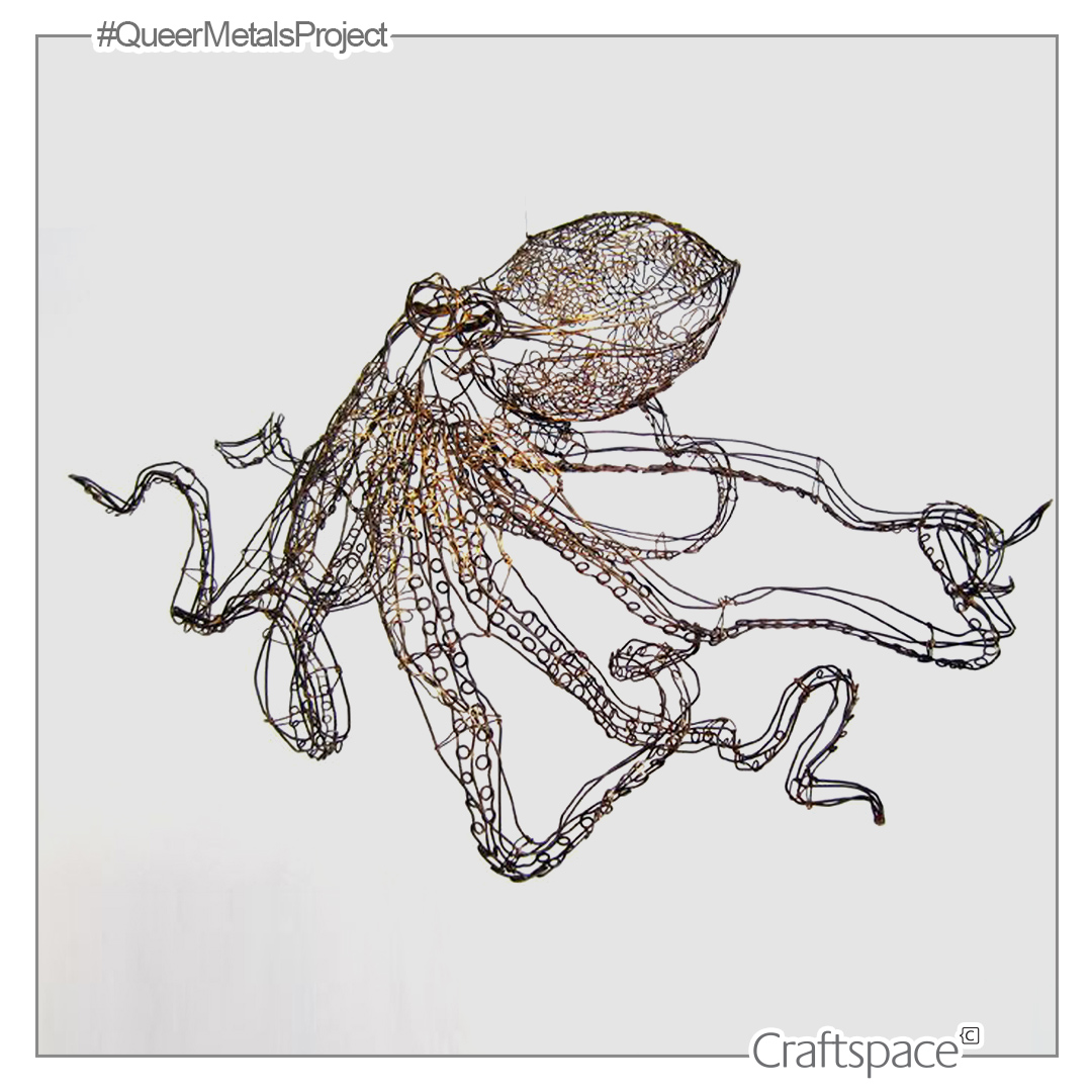 Rust coloured octopus form made of steel wire floats against an off white background