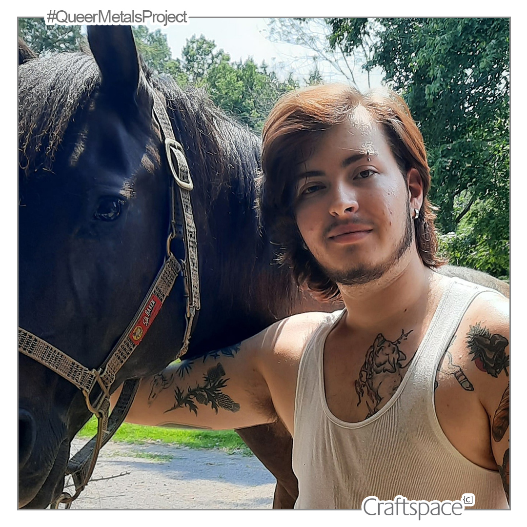 a person wearing a tank top with tattoo visible on their body stands next to a black horse.