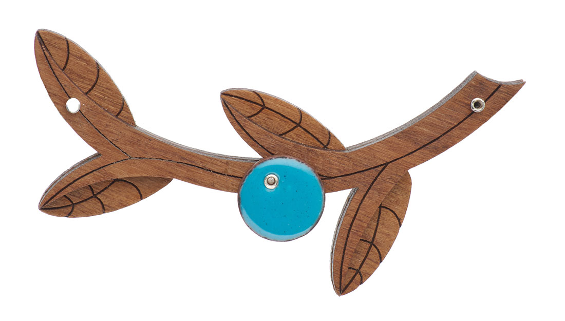 a brooch of walnut wood in the shape of a curved olive branch with a turquoise enamel circle in the centre, on a white background.