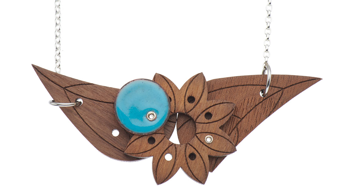 a necklace with a pendant made of walnut wood in an abstract floral shape with a circle of turquoise enamel on the top at the centre, on a white background.