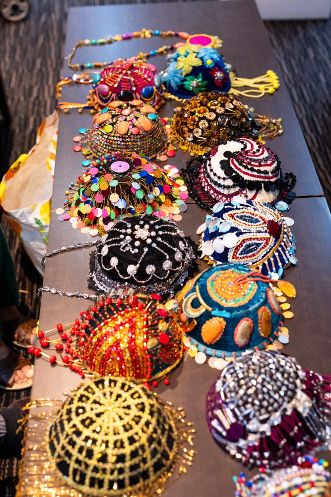 Two rows of velvet Kurdish women's caps made by Zohra, each embellished with sequins, beads and stones of all different colours and shapes.