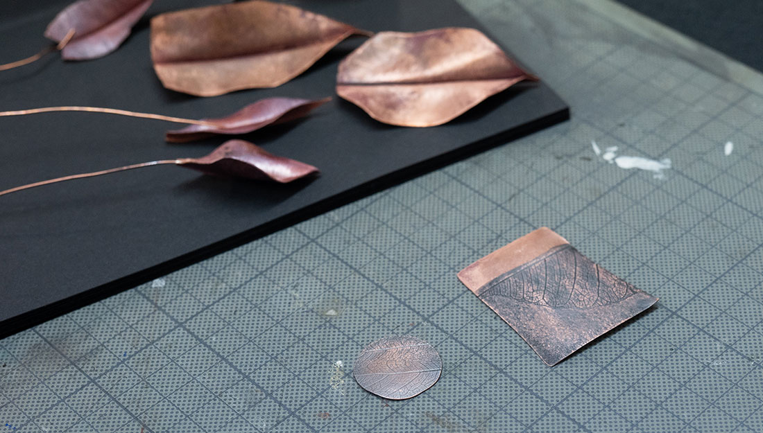 CraftingPathways_Megan&Nobuko_PhotoHayleySalter_4 A close-up of copper leaves, formed and coloured, as well as a copper imprinted with the texture of a leaf.