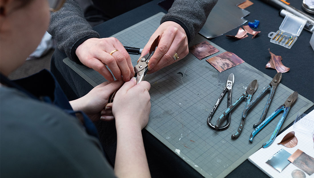 CraftingPathways_Megan&Nobuko_PhotoHayleySalter_5 A close-up of Nobuko and Megan's hands. Megan is being shown how to use metal cutters,