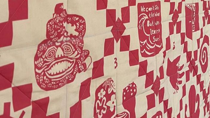 A red and white patterned quilt with graphic drawings of artworks.